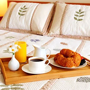 Πρωινό στο κρεβάτι με καφέ, χυμό και κρουασάν — άνετη διαμονή ξενοδοχείου